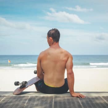 Photograph of a skateboarder sitting on the steps above an Australian beach.